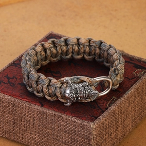 Close-up of paracord bracelet with metallic skull buckle on a textured gift box