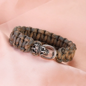 Detail of paracord bracelet with silver skull crown clasp on silk background
