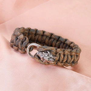 Detail of paracord bracelet featuring a vintage silver skull clasp on silk background
