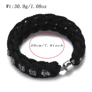 Macro shot of men's black braided rope bracelet with silver skull charms and screw clasp