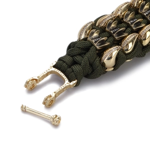 Macro shot of dark green paracord bracelet with gold eagle claw charms and crystal accents