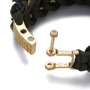 Close-up of olive green woven bracelet with gold metal screw clasp and industrial texture