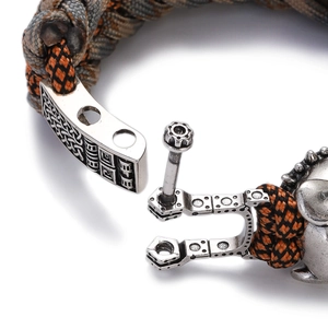 Macro detail of men's woven paracord bracelet with vintage geometric engraved clasp