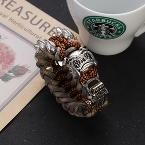 Macro view of woven paracord bracelet with a metal bulldog buckle and silver claw charms