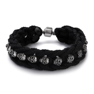 Detail of men's black woven rope bracelet with vintage silver skull charms and magnetic clasp