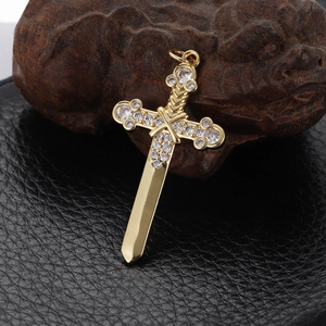 Macro shot of gold cross-dagger pendant with sparkling zircon inlays on dark wood background