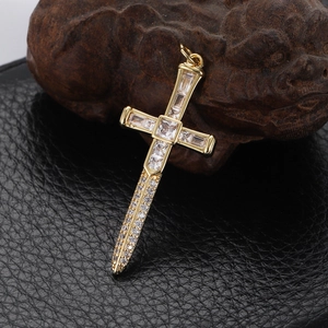 Macro shot of a gold-plated cross pendant with cubic zirconia on black leather surface