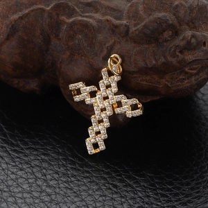 Macro detail of a gold-plated cross pendant with micro-pave zircon crystals on leather