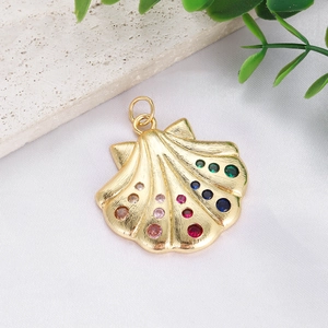 Macro shot of 18K gold plated shell pendant with colorful inlaid gemstones and ribbed texture