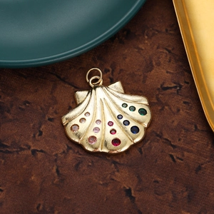Detail of vintage 18K gold shell pendant with colorful zircon stones and brushed metal texture