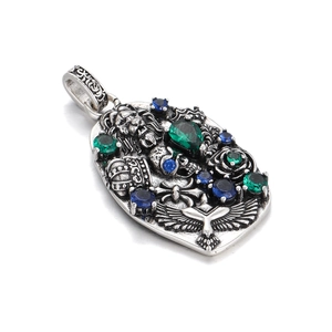 Macro view of gothic silver pendant with lion, skull, eagle and colored gemstones