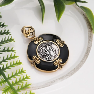 Detail of vintage portrait medal pendant with black enamel and gold frame on white ceramic