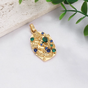 Close-up of golden vintage baroque pendant with lion emblem and colorful gemstones