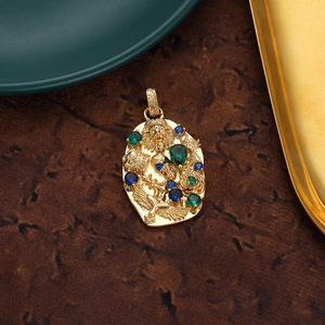 Close-up of vintage 18K gold lion head pendant with green and blue gemstones detail