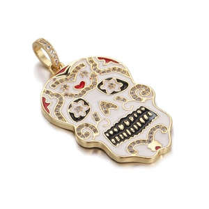 Macro shot of gold plated hip hop sugar skull pendant with white enamel and rhinestones