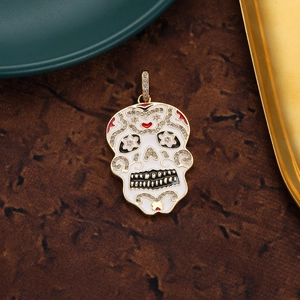Macro view of a 18K gold-plated sugar skull pendant with white enamel and zircons