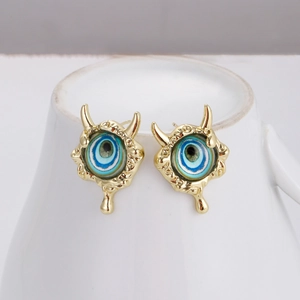 Detail of gold devil eye earrings with gradient blue center and horn accents