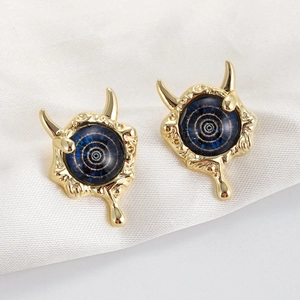 Detailed close-up of gold-plated devil horn stud earrings with blue spiral eye design