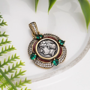 Detail of vintage bronze coin pendant with emerald stones and white zircon crystals