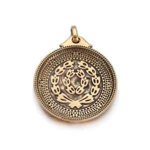 Detail view of round vintage bronze coin pendant with floral relief and dot texture
