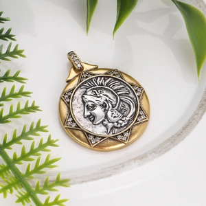 Macro shot of bronze Roman coin pendant with gold star frame and zircon inlay on white plate