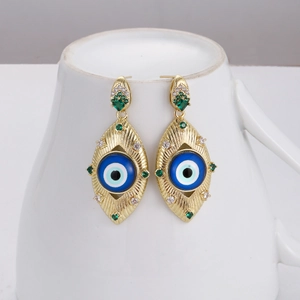 Detail of golden devil eye drop earrings with blue enamel and green zircon stones