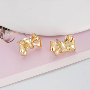 Nahaufnahme der goldenen Ohrstecker in Schleifenform mit mattem Metallic-Finish