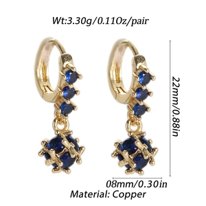 Macro shot of 18K gold plated earrings with blue zircon stones and ball pendants