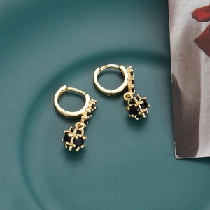 Macro detail of 18K gold plated hoop earrings with black zircon globe pendants