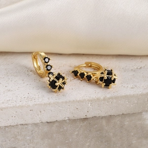 Detail of 18K gold hoop earrings with black zircon spheres on natural stone