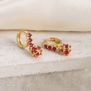 Macro detail of 18K gold plated hoop earrings with red zircon and luxury globe pendant