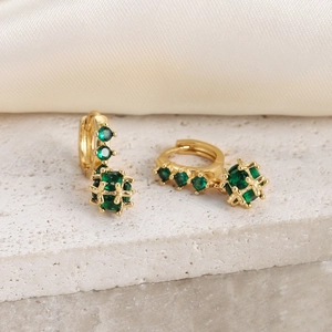 Detail view of 18K gold-plated hoop earrings with green zircon hollow sphere pendant