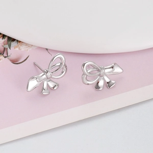 Makroaufnahme von silbernen Schleifenohrringen mit polierter Oberfläche auf Pink
