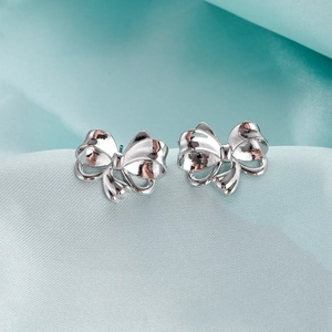 Nahaufnahme polierter Schleifenohrstecker auf hellblauem Seidenstoff Hintergrund