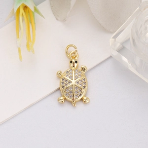 Detail of 18K gold-plated turtle pendant with sparkling cubic zirconia on a warm background