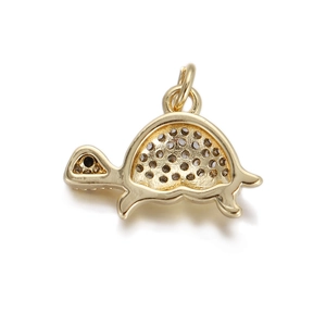 Detailed view of a gold turtle pendant with micro-inlaid dark crystals and polished finish