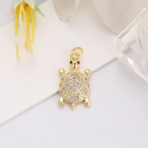 Close-up of golden turtle pendant with white zircon pavé and heart pattern details
