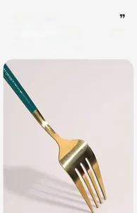 Detailed close-up of a modern gold dinner fork with a dark green handle finish