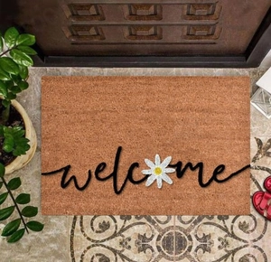 Detailed texture of brown entryway mat with welcome text and small daisy floral design
