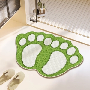Close-up of green cartoon foot-shaped bath mat with thick plush texture and non-slip edge