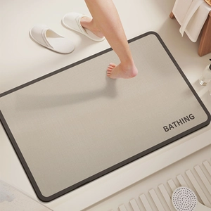 Detail of a beige diatom mud bath mat with a black border and BATHING text print
