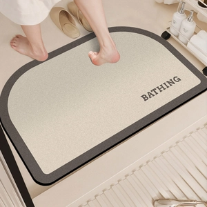 Detailed top view of a beige semi-circle diatom mud bath mat with BATHING text in bathroom