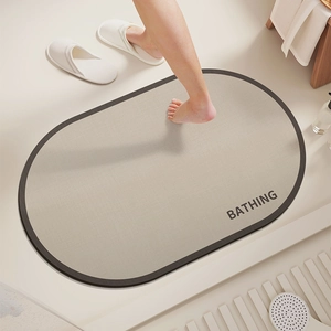 Detail of oval anti-slip bath mat in beige with BATHING text and absorbent texture
