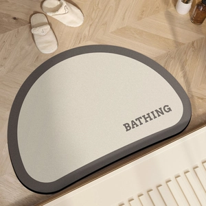 Detail view of semi-circular diatom mud bath mat with BATHING text on wood floor