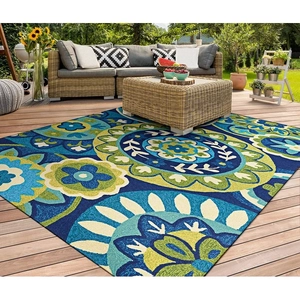 Detail of floral mandala outdoor rug on wooden deck with wicker patio furniture