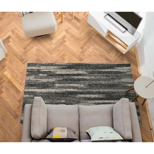 Top view of modern abstract striped rug in gray and black on wood herringbone flooring