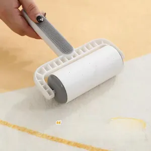 Handheld lint roller removing debris from a minimalist faux cashmere rug surface