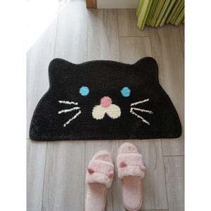 Cute black cat shaped faux cashmere floor mat with non-slip texture on light wood floor
