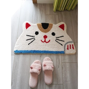Vertical top view of a cartoon cat bath mat with plush pink slippers on grey wooden floor