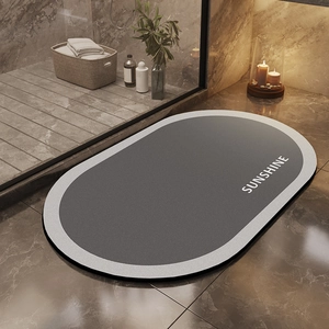 Close-up of gray oval diatomite bath mat with Sunshine text on marble floor